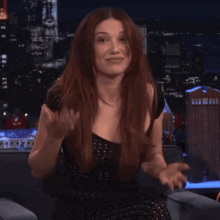 a woman with long red hair is sitting in front of a city skyline