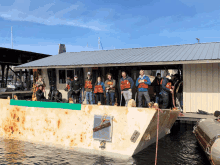 a group of people standing on a boat in front of a building with a sign that says ' a ' on it