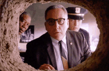 a man in a suit and tie is looking through a hole