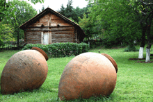 two large clay pots are sitting in the grass in front of a wooden house