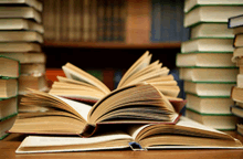 a stack of books sits on a table with one open