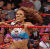 a woman in a bikini is standing in a wrestling ring with her hair blowing in the wind