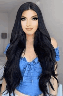 a woman with long black hair is wearing a blue crop top .