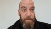 a bald man with a beard is making a face