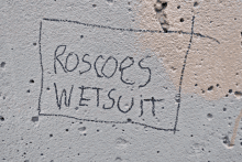 a roscoe 's wetsuit sign is written on a concrete wall