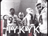 a group of football players are standing in a locker room .