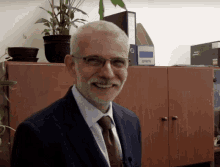 a man in a suit and tie is smiling in front of a cabinet with a binder that says ' security ' on the front