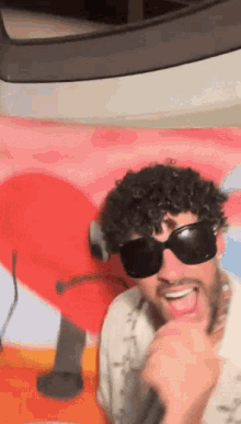 a man with curly hair wearing sunglasses is singing into a microphone .