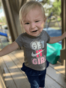 a little girl wearing a gray shirt that says get it girl