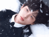 a close up of a person laying down with feathers on their face