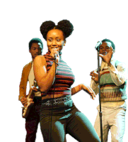 a woman singing into a microphone while two men play guitars