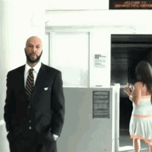 a man in a suit and tie stands in front of a sign that says welcome to ontario intl airport