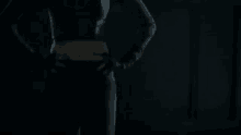 a woman in a black outfit is standing in a dark room with her hands on her hips .