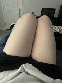 a woman 's legs are crossed on a bed with a laptop in the background