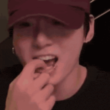 a close up of a person wearing a hat and eating a piece of food .