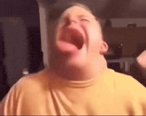 a young boy is making a funny face with his tongue out .