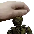 a hand is holding a toy on top of a statue of a robot .