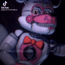 five nights at freddy 's foxy is wearing a pink bow tie and a microphone .