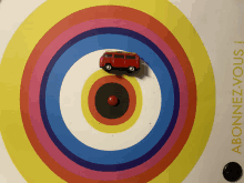 a colorful target with a red toy van in the center