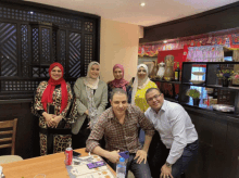 a group of people posing for a picture in a restaurant with a coke can on the table