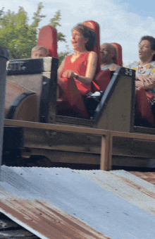 a woman laughs while riding a roller coaster with other people