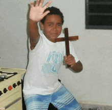 a young boy is holding a wooden cross in his hands and waving .