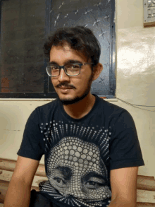 a young man wearing glasses and a black shirt with a polka dot face on it