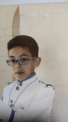 a boy wearing glasses and a white uniform looks at the camera