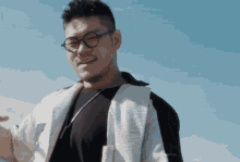a man wearing glasses and a black shirt looks at the camera