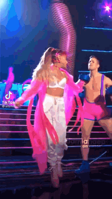 ariana grande is performing on stage with a man in a pink outfit .