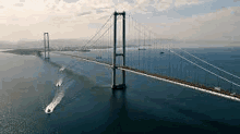 an aerial view of a bridge over a body of water with boats going under it .