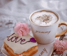 a cup of coffee sits next to a piece of cake with the word love written on it