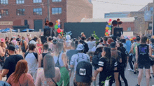 a crowd of people are gathered in front of a stage with balloons and a sign that says ' rm '