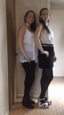 two women standing next to each other in a hallway wearing high heels