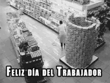 a black and white photo of a man standing in a grocery store next to a stack of boxes .