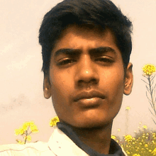 a close up of a young man 's face with flowers in the background