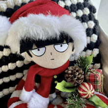 a stuffed toy wearing a santa hat and scarf sits next to a christmas tree