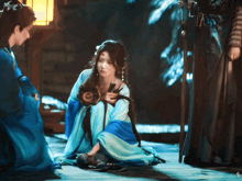 a woman in a blue dress is kneeling down next to a man in a blue robe