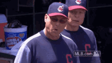 two baseball players are standing next to each other in a dugout with a bucket of bubble bubbles in the background