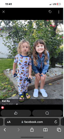 two little girls are posing for a picture on a cell phone