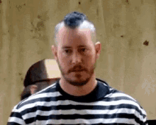 a man with a mohawk and beard wearing a striped shirt .