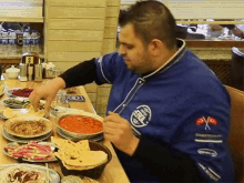 a man wearing a blue shirt that says ' turkey ' on it is sitting at a table eating food