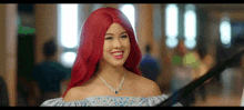 a woman with red hair is wearing a necklace and a blue dress .