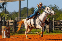 a woman is riding a white horse in a rodeo arena with a barrel that says pk on it