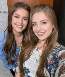 two beautiful young women are posing for a picture together and smiling for the camera .