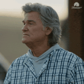 a man in a plaid shirt is standing in front of a sign that says paramount