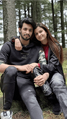 a man and a woman are posing for a picture in the woods and the man is wearing a black sweatshirt that says inverted