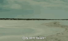 a man is carrying a woman on his shoulders on a beach and says `` on my way '' .
