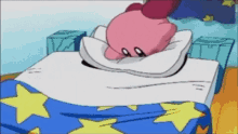 kirby is laying on a bed with a blue and yellow blanket