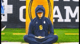 a man wearing a hoodie is sitting in a lotus position on a field .